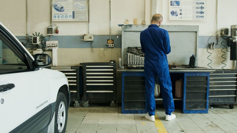 A man using a multi-purpose cleaner and sponge to clean a table indoors, emphasizing hygiene.
